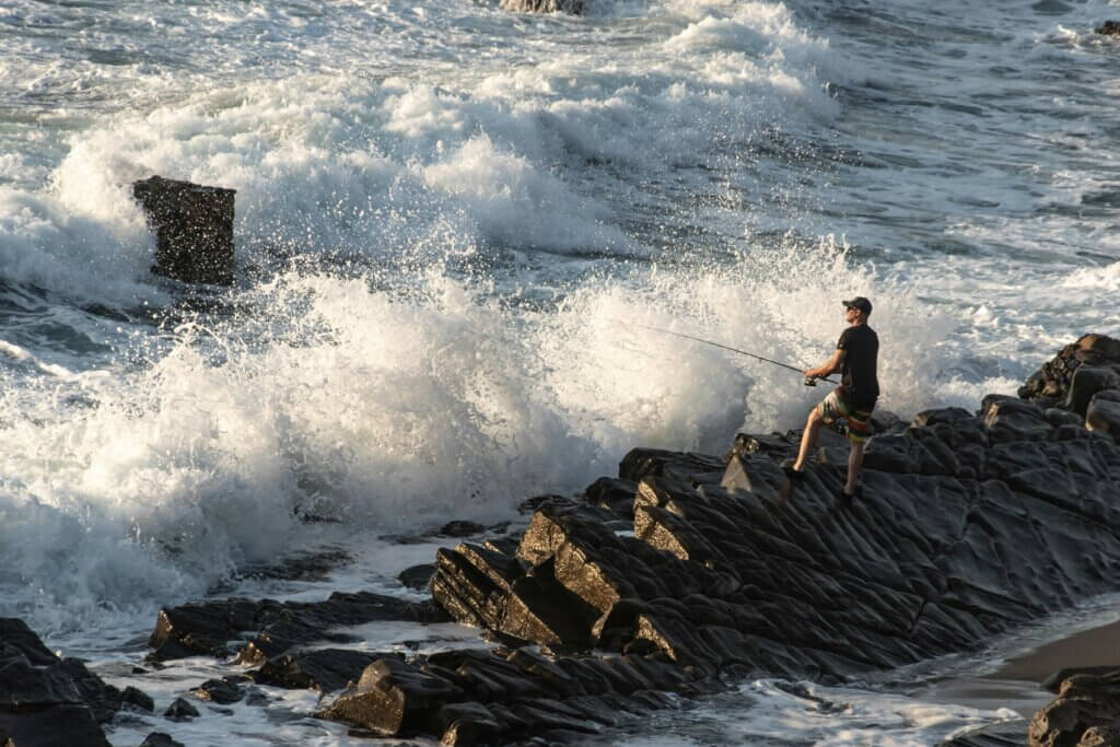 homme pechant au bord avec beaucoup de vagues